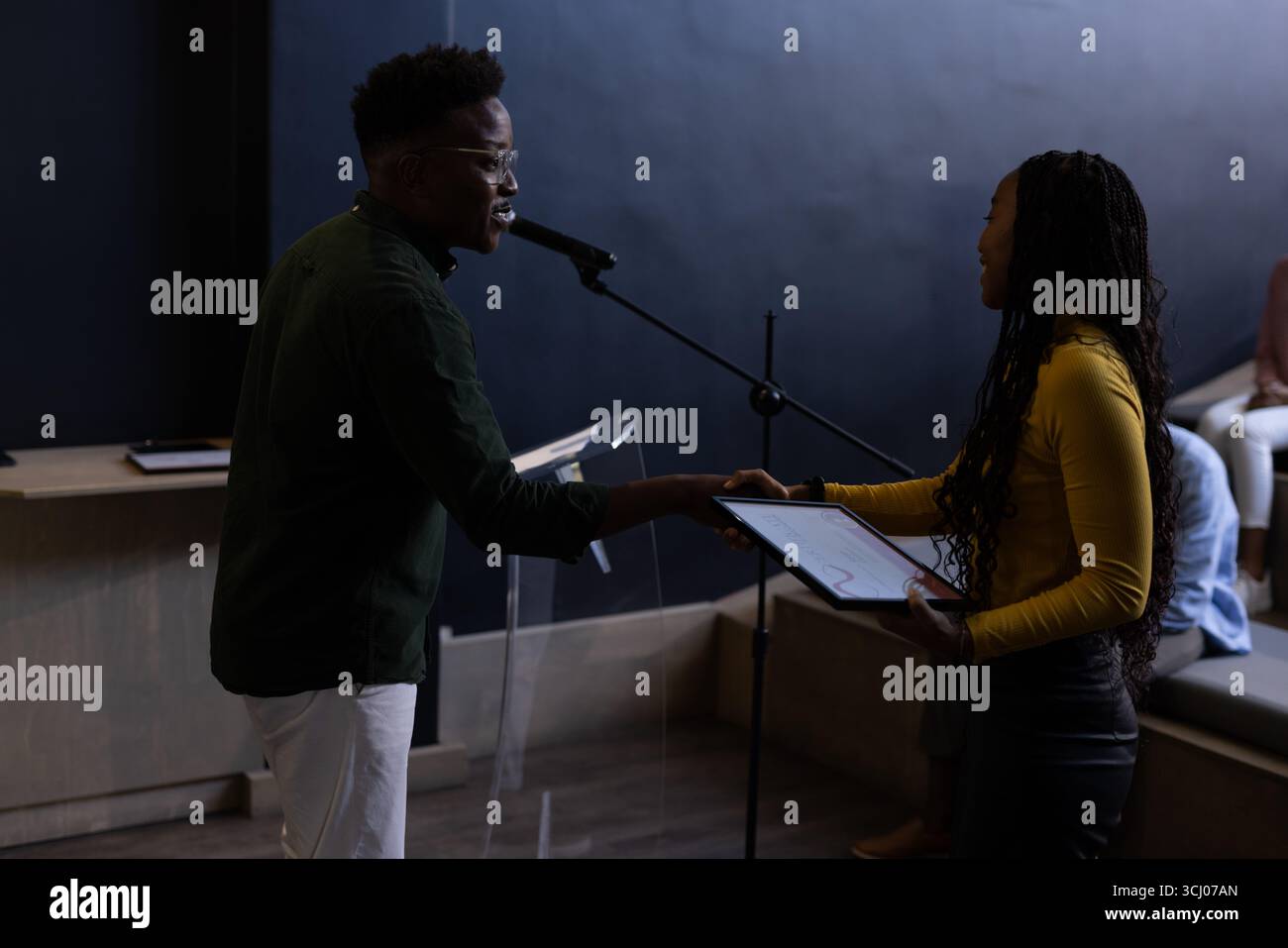 Uomo che presenta un premio alla donna sul palco durante una conferenza d'affari Foto Stock