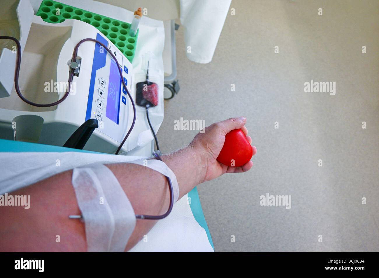 Paziente che dà sangue spremendo una palla di stress a forma di cuore in un centro medico. Foto Stock