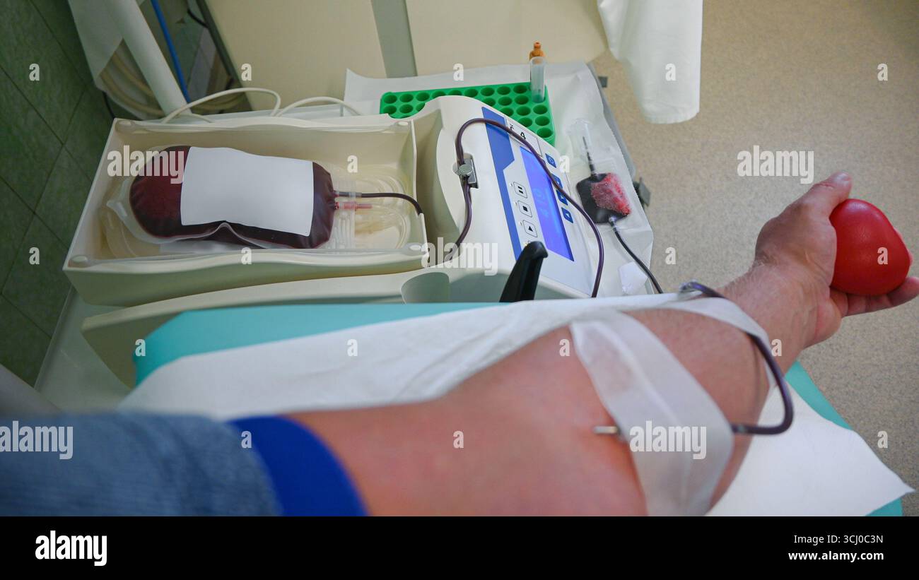 Paziente che stringe palla di stress mentre donano sangue in ospedale con moderne attrezzature mediche. Foto Stock