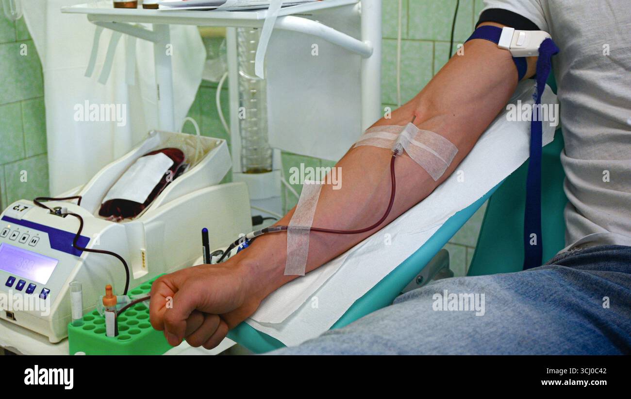 Paziente che dà sangue in una struttura medica, utilizzando tecnologie avanzate per un processo di donazione sicuro ed efficiente. Foto Stock