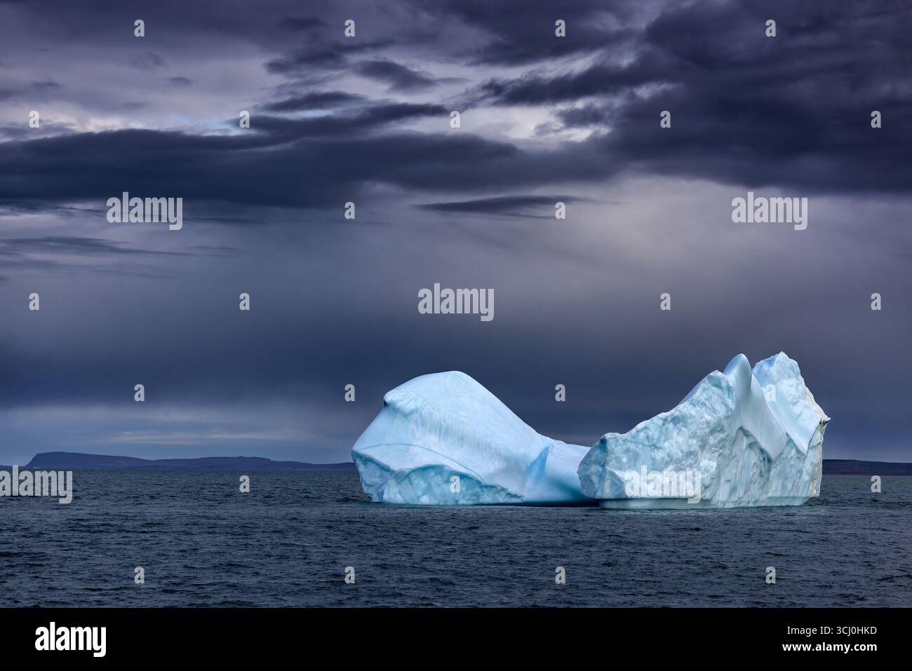 Maestoso iceberg blu nell'Oceano Artico. Al largo della costa dell'isola Bontecoe o, nel mare della Groenlandia. Cielo tempestoso con elaborazione oscura e lunare. Foto Stock
