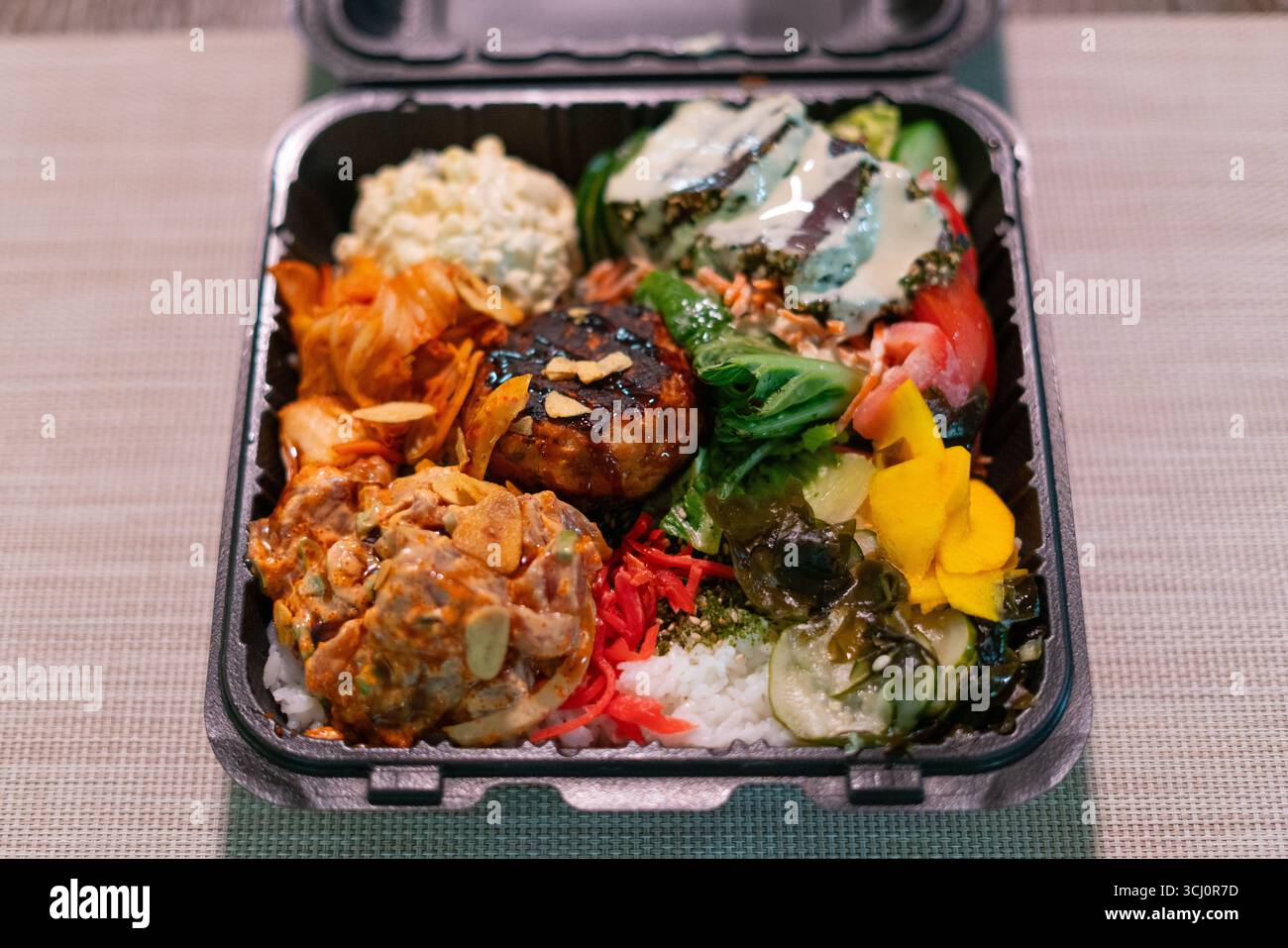 Pranzo in stile hawaiano con piccante, torta di granchio scottata, insalata di maccheroni, kimchi, verdure sottaceto, e riso. Fusione di sapori isolani Foto Stock