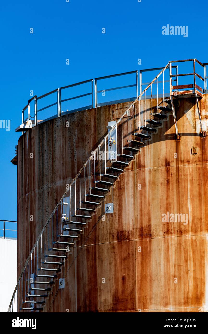 Grandi serbatoi di stoccaggio industriali arrugginiti contro il cielo blu. Foto Stock