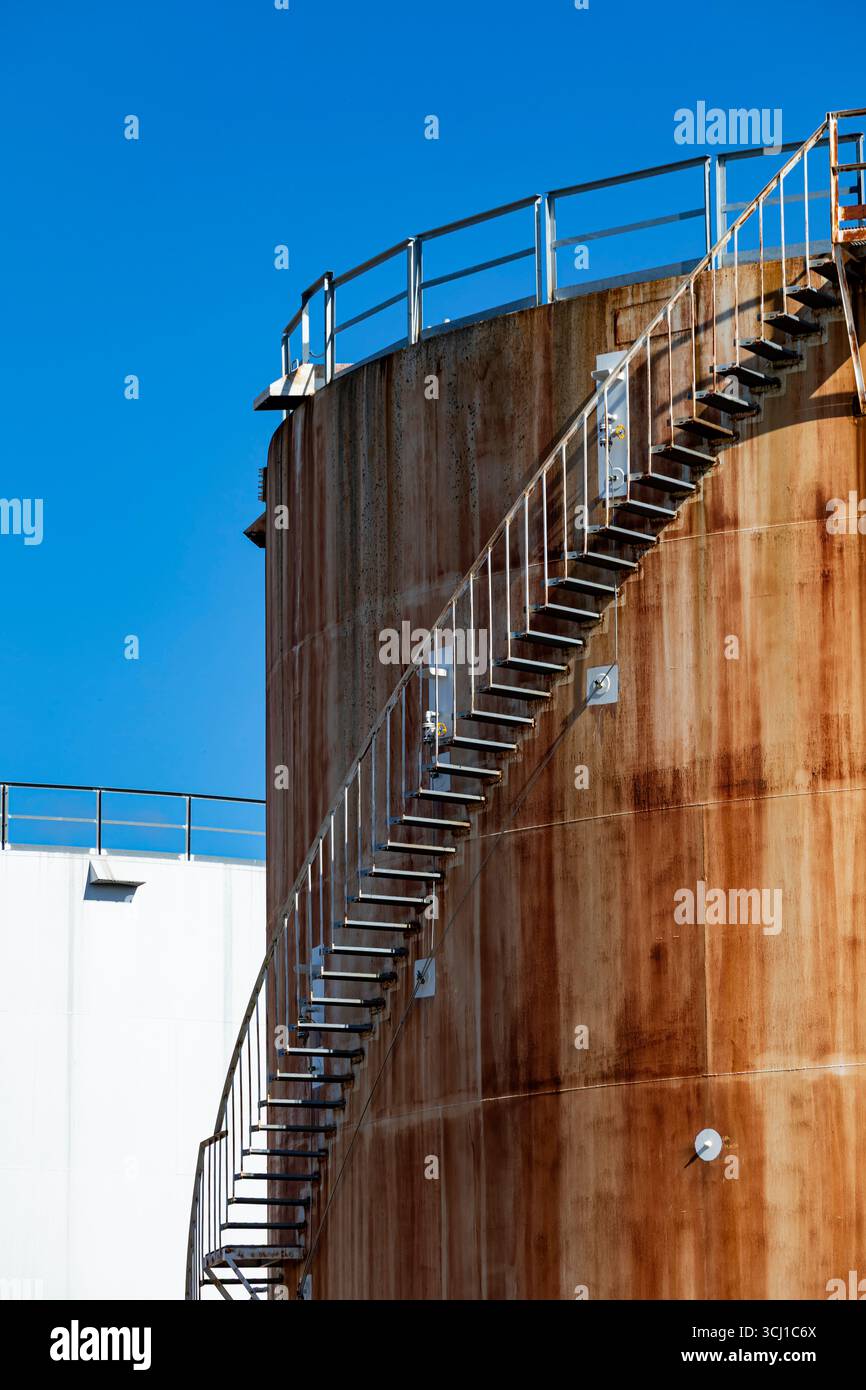 Grandi serbatoi di stoccaggio industriali arrugginiti contro il cielo blu. Foto Stock