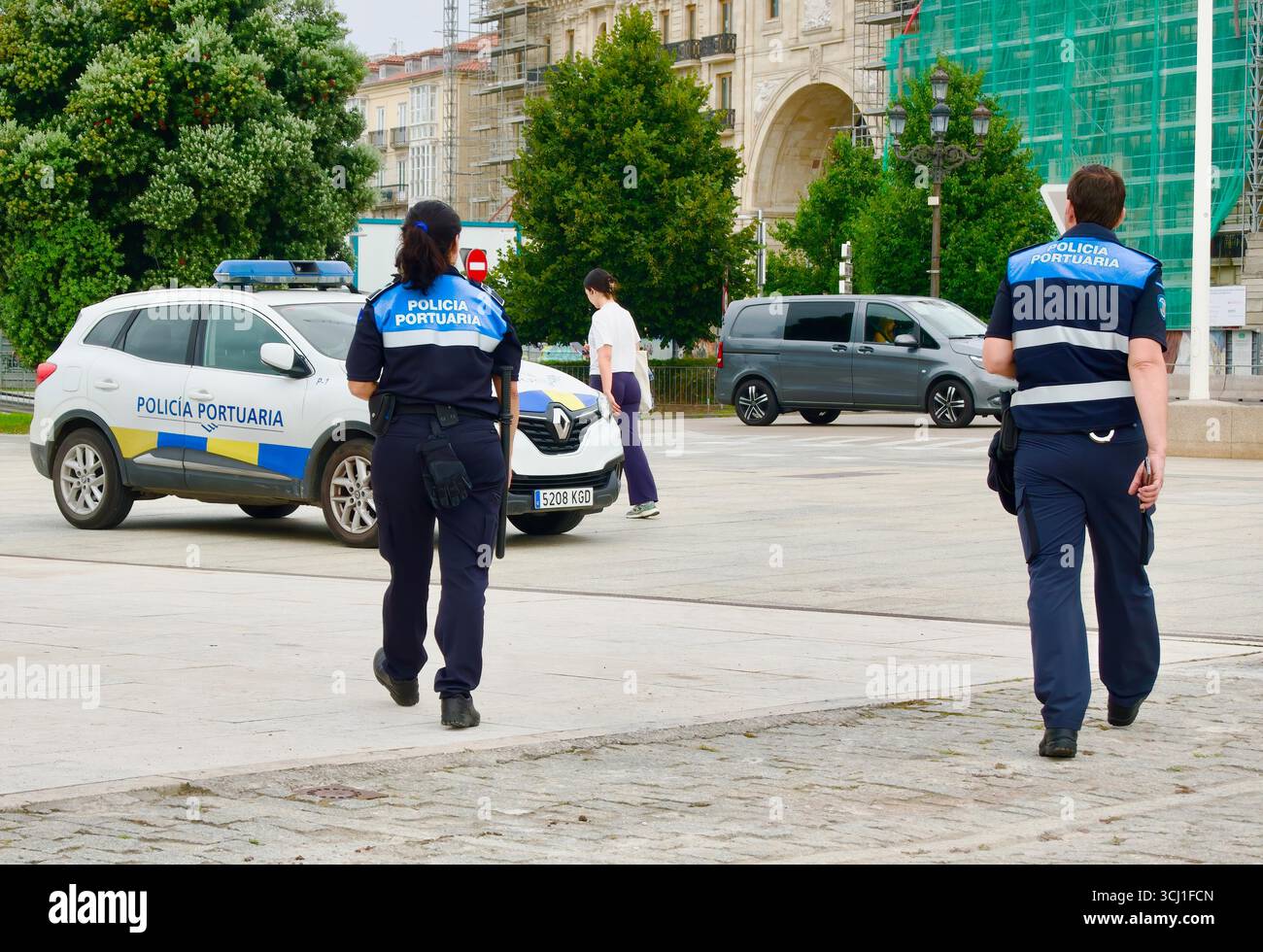 Agenti di polizia portuale in uniforme che camminano verso un'auto di polizia parcheggiata nel centro della città vicino alla baia Paseo Maritimo Santander Cantabria Spagna Europa Foto Stock