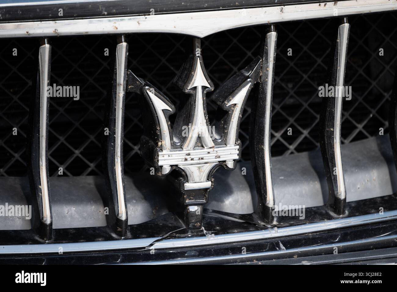 Il logo del tridente Maserati è il simbolo del produttore italiano di auto di lusso. Primo piano del fregio nella griglia del radiatore. Gli insetti morti ci stanno attaccando. Foto Stock