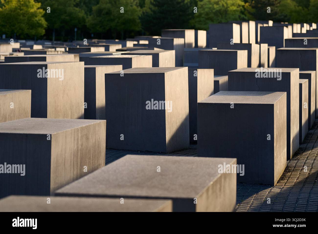 Blocchi geometrici in cemento del Memoriale dell'Olocausto di Berlino al tramonto, ampio orientamento del paesaggio, forte illuminazione laterale, composizioni architettoniche minimalistiche Foto Stock