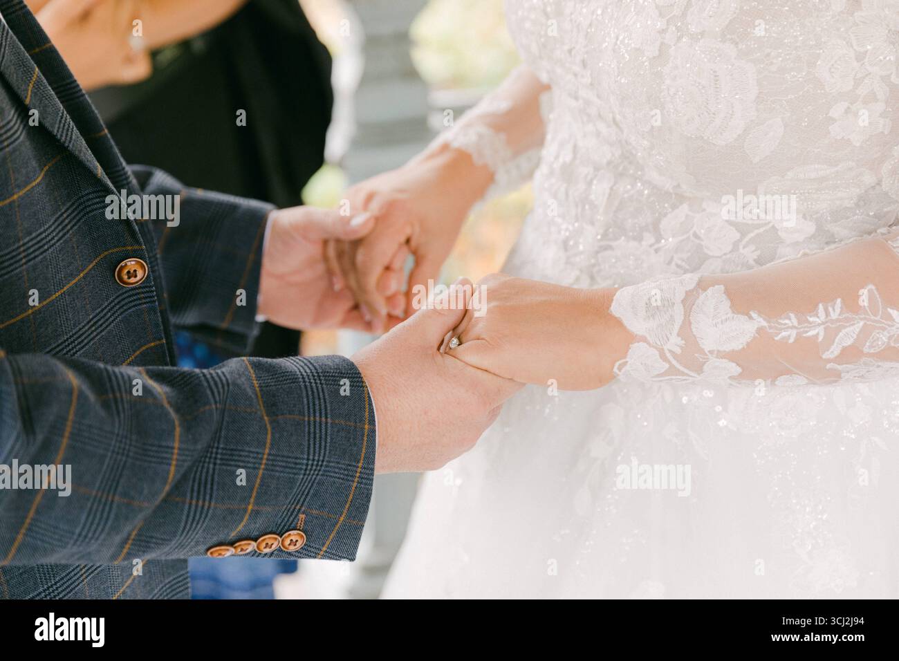 Due persone si tengono per mano mentre si scambiano le nozze in un giardino sereno pieno di vegetazione lussureggiante. Foto Stock