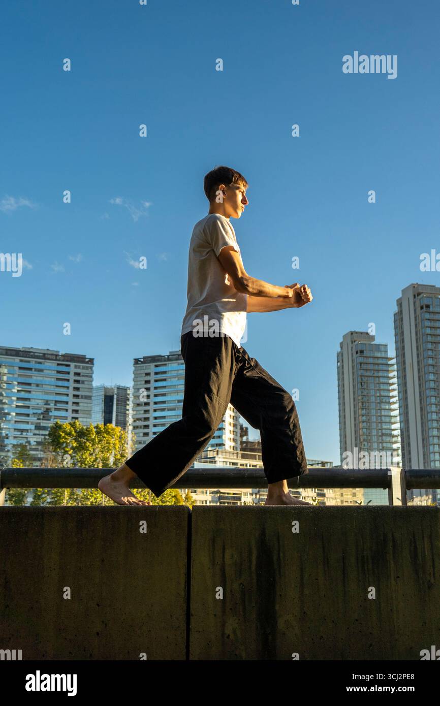 Ripresa verticale di un allenamento di arti marziali in solitaria in una giornata di sole in città. Foto Stock