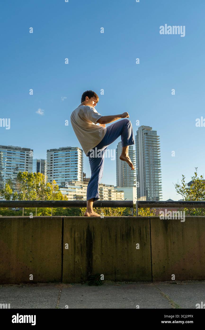 Giovane artista marziale che esegue la gru posa in una città moderna Foto Stock