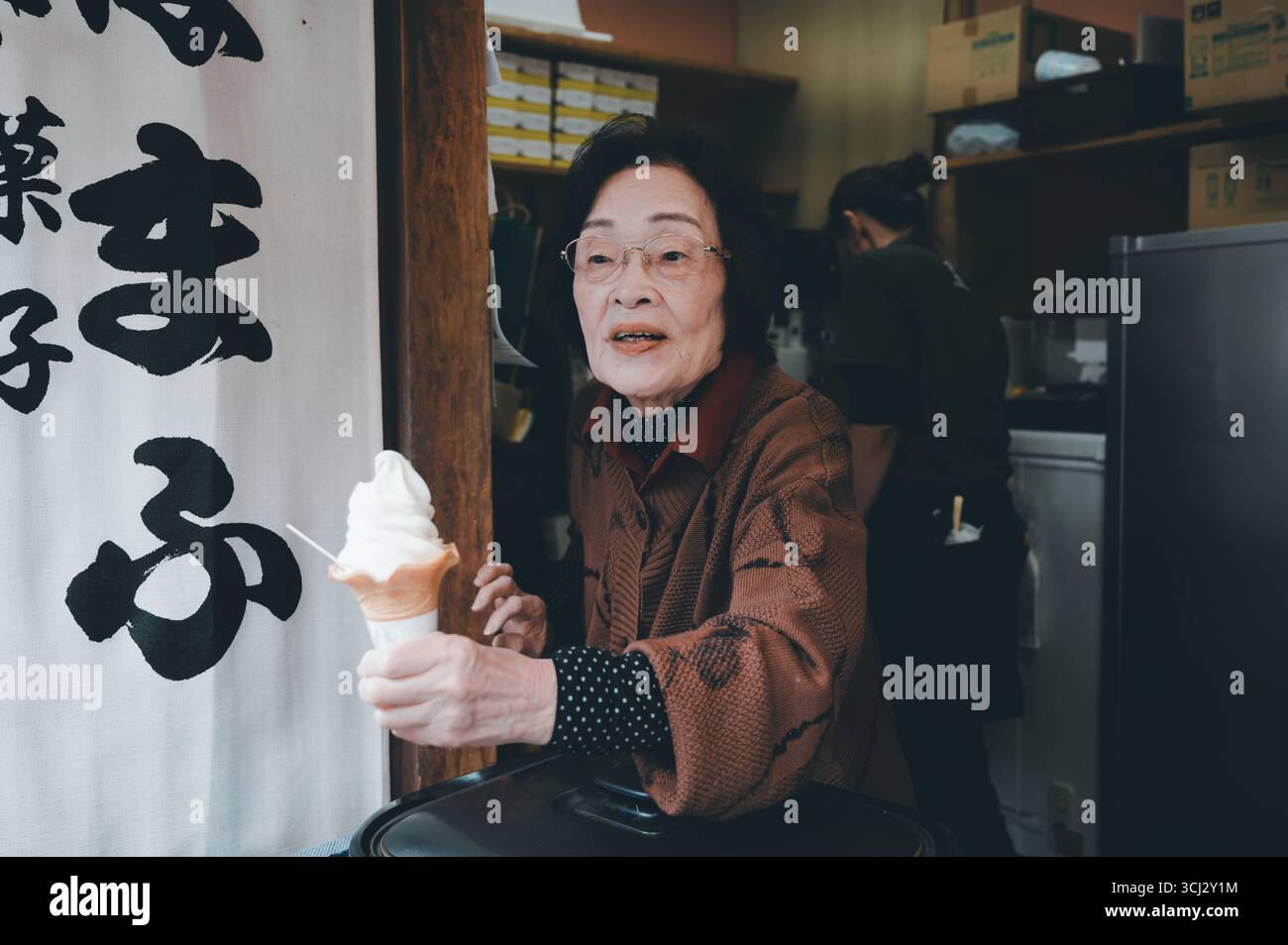 Un venditore anziano consegna un gelato morbido da un piccolo negozio di Kyoto Foto Stock