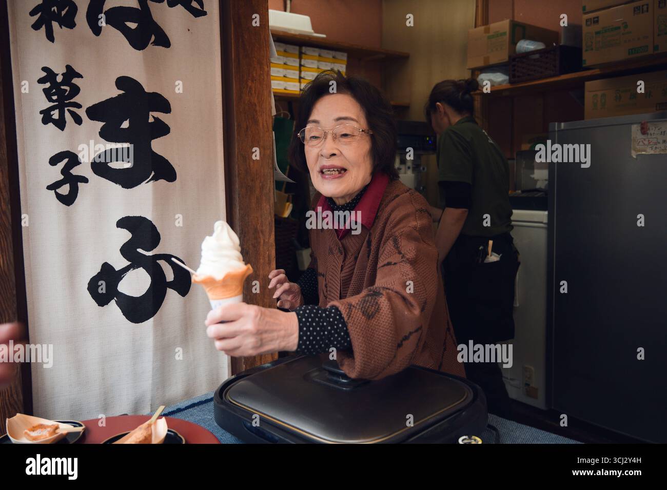 Un venditore anziano consegna un gelato morbido al cliente da un piccolo negozio di Kyoto Foto Stock