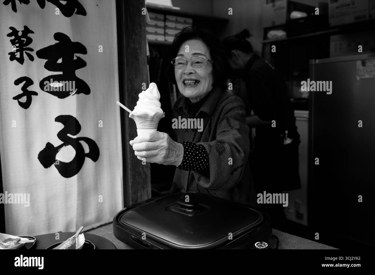 Venditore anziano con gelato soft servito da un piccolo negozio di Kyoto in bianco e nero Foto Stock