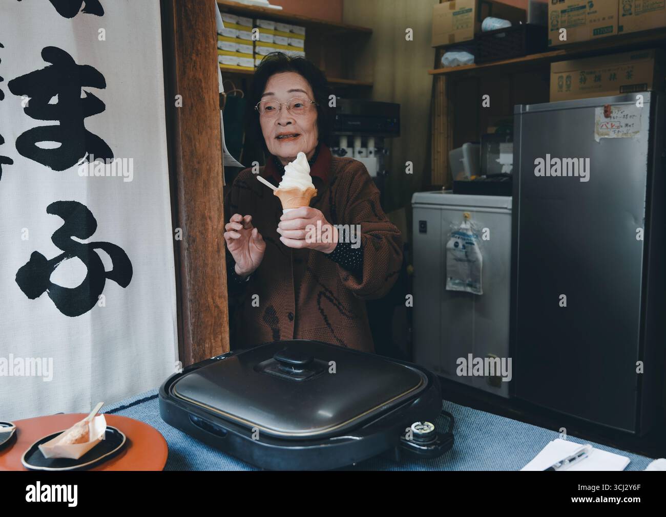 Venditore anziano che porta un gelato a servizio morbido da un piccolo negozio di Kyoto Foto Stock