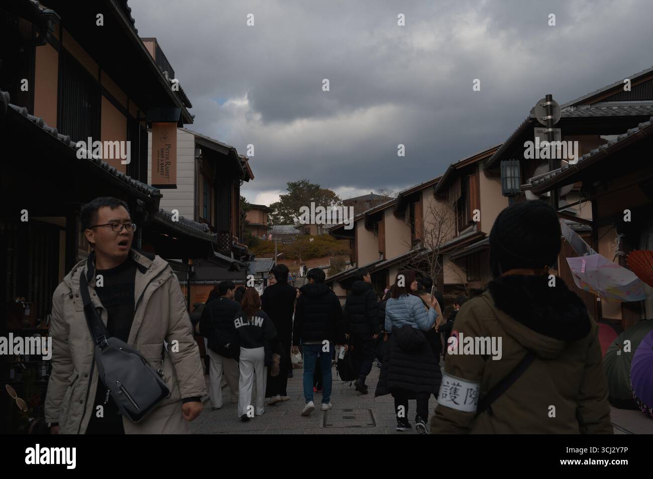 Il quartiere di Higashiyama a Kyoto, con gente che cammina tra le tradizionali case di legno sotto un cielo invernale mostruoso Foto Stock