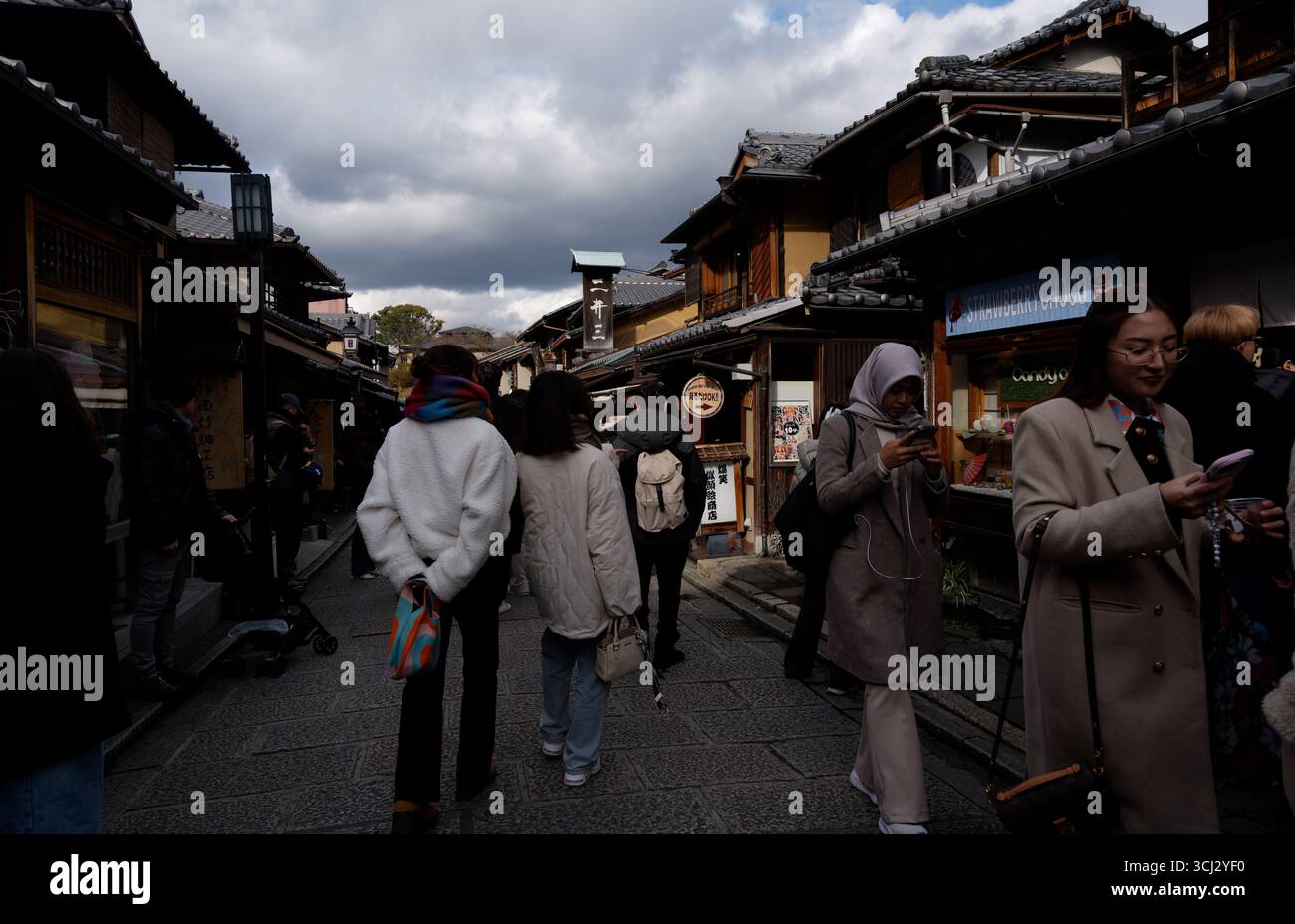 Vita di strada nel quartiere di Higashiyama a Kyoto, la luce invernale cade sui tradizionali punti vendita in legno Foto Stock