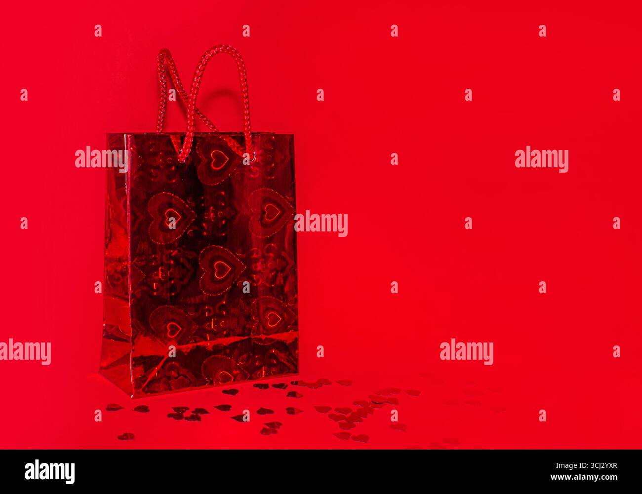 Borsa per la spesa rossa su sfondo rosso con coriandoli rossi e spazio per le copie. Foto Stock