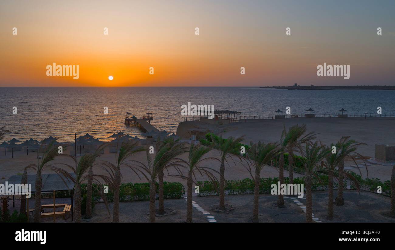 Vista dell'alba da un hotel sulla spiaggia e sul molo che conduce al mare. Foto Stock