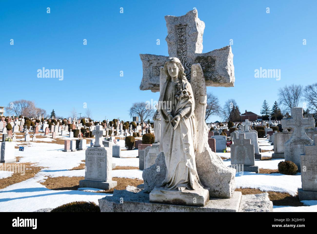 Un'elaborata scultura in pietra di una croce e la statua di un angelo alato in un cimitero di Toronto Foto Stock