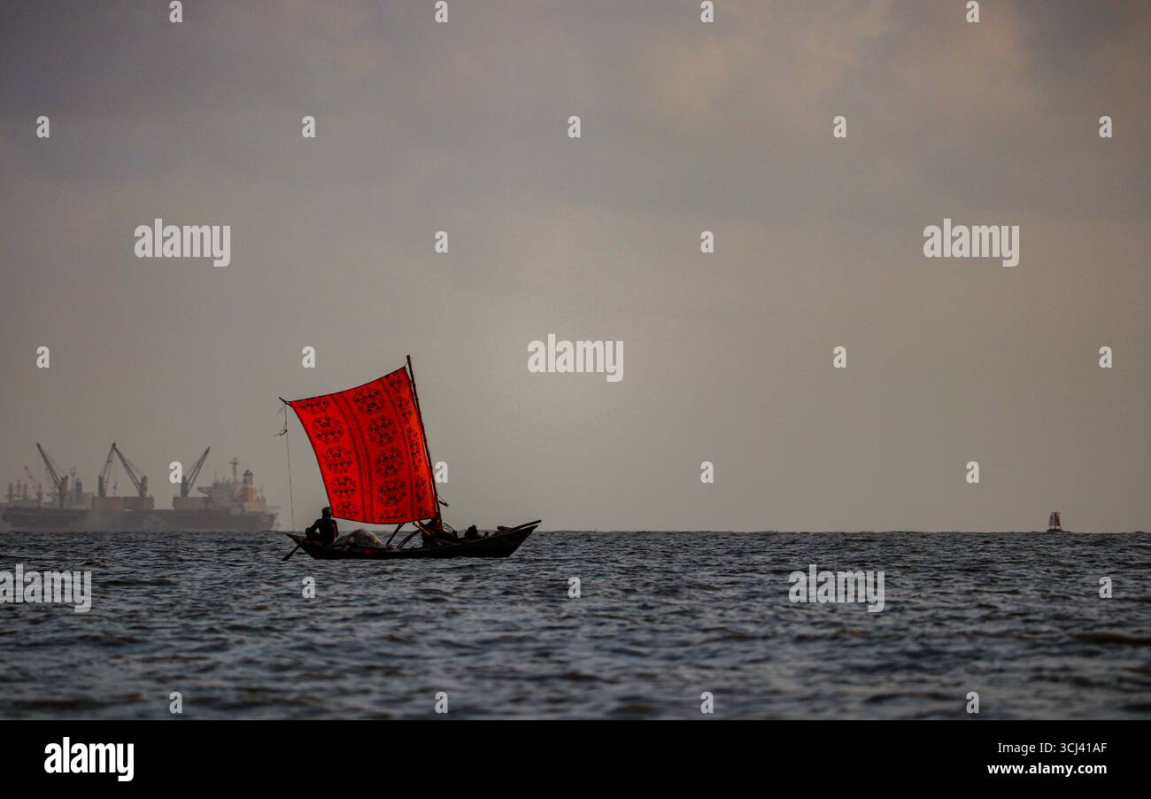 Lo splendido paesaggio di una barca in legno artigianale con una vivace vela rossa a motivi geometrici scivola attraverso la Baia del Bengala, riflettendo il patrimonio senza tempo di Foto Stock