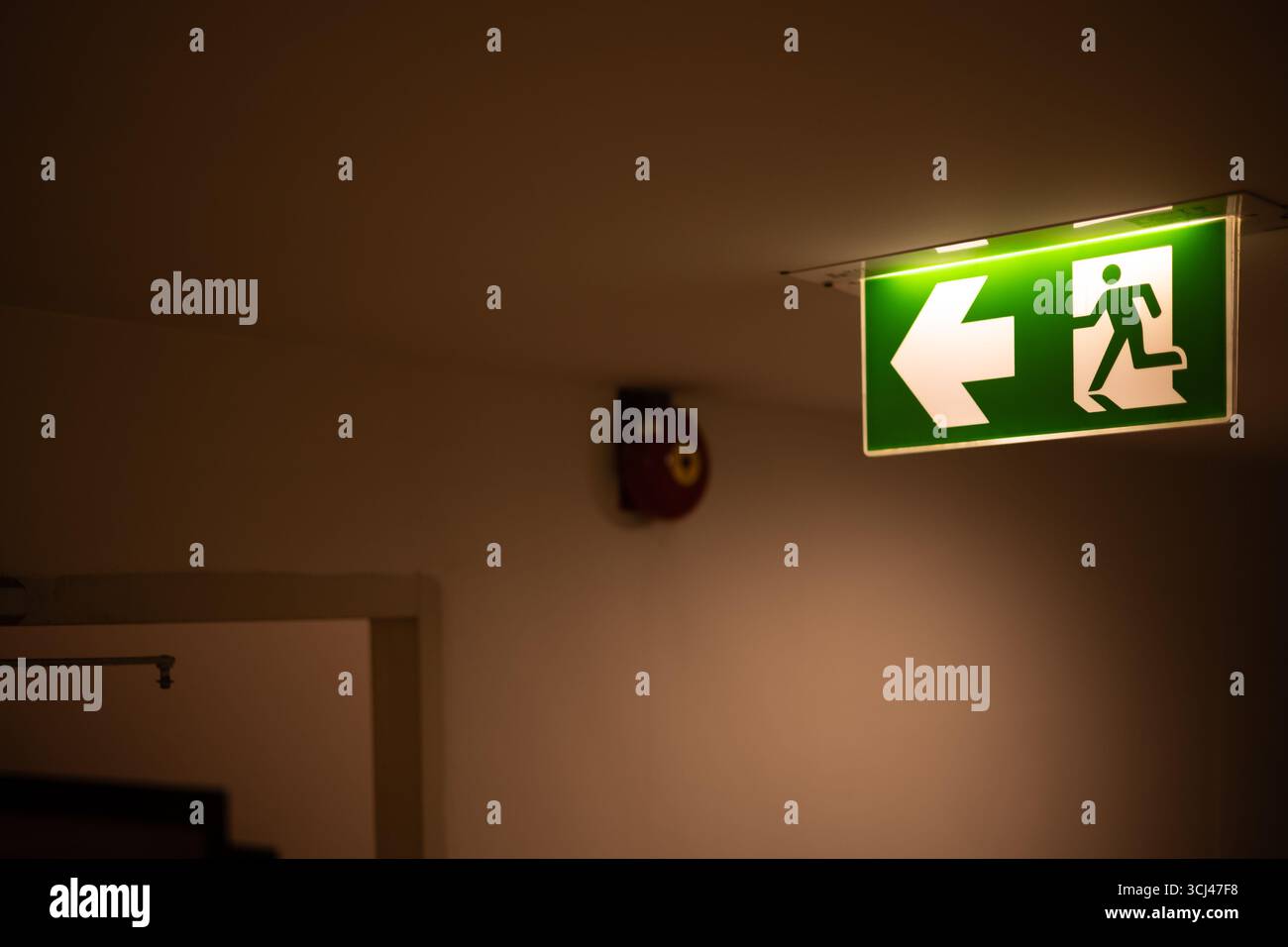 Uscita direzione freccia direzione direzione, segnale guida uscita luce verde segnale uscita di emergenza in una stanza buia installazione sul corridoio dell'edificio a soffitto corri Foto Stock