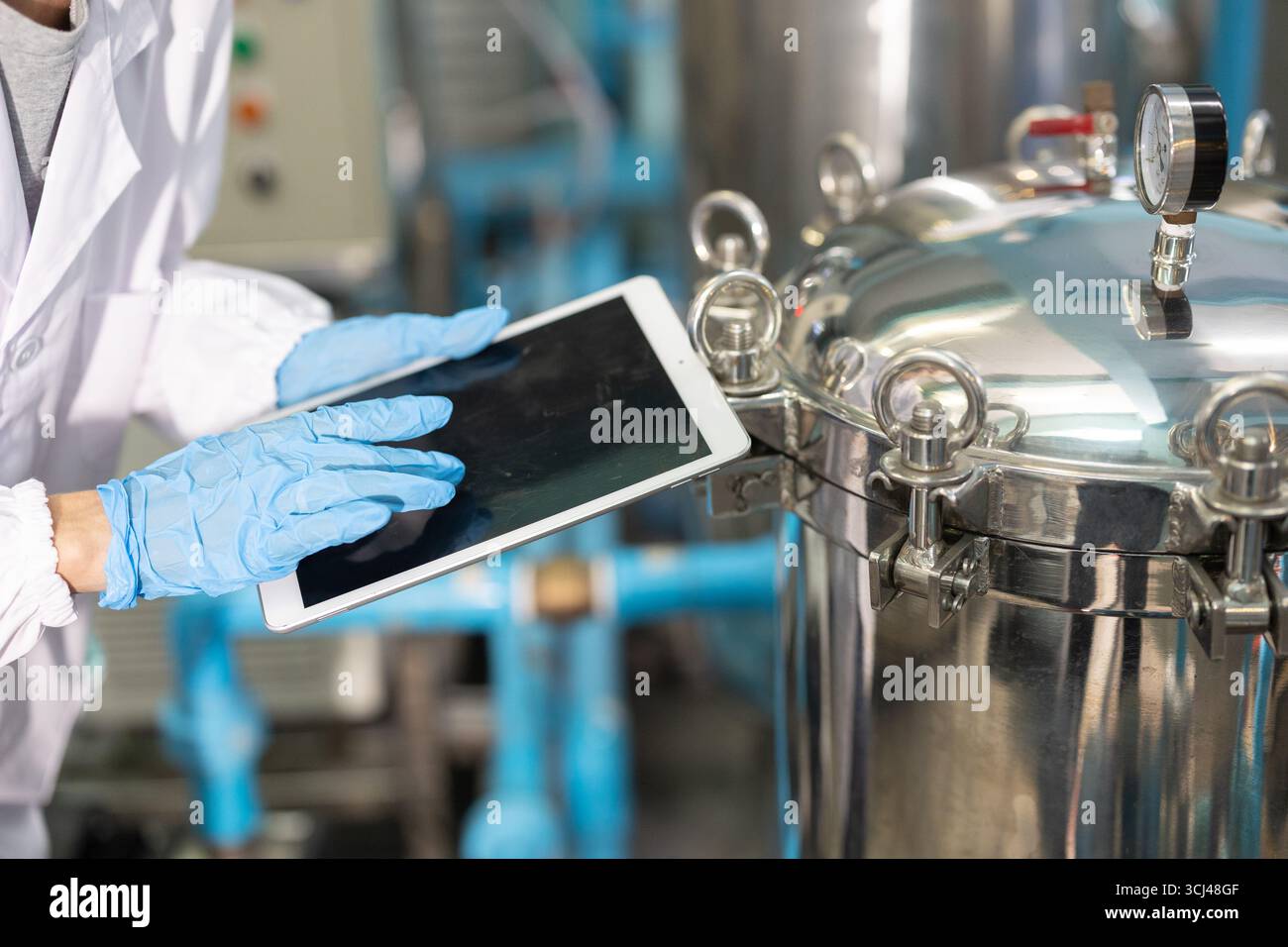 primo piano personale mano lavoro in scienza laboratorio medico fabbrica controllare record serbatoio di pressione con compressa Foto Stock