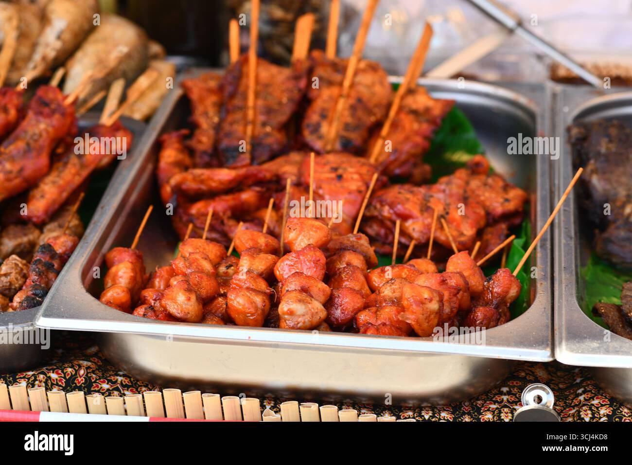 Spiedini di carne tailandese marinati rossi grigliati al mercato Street food Foto Stock