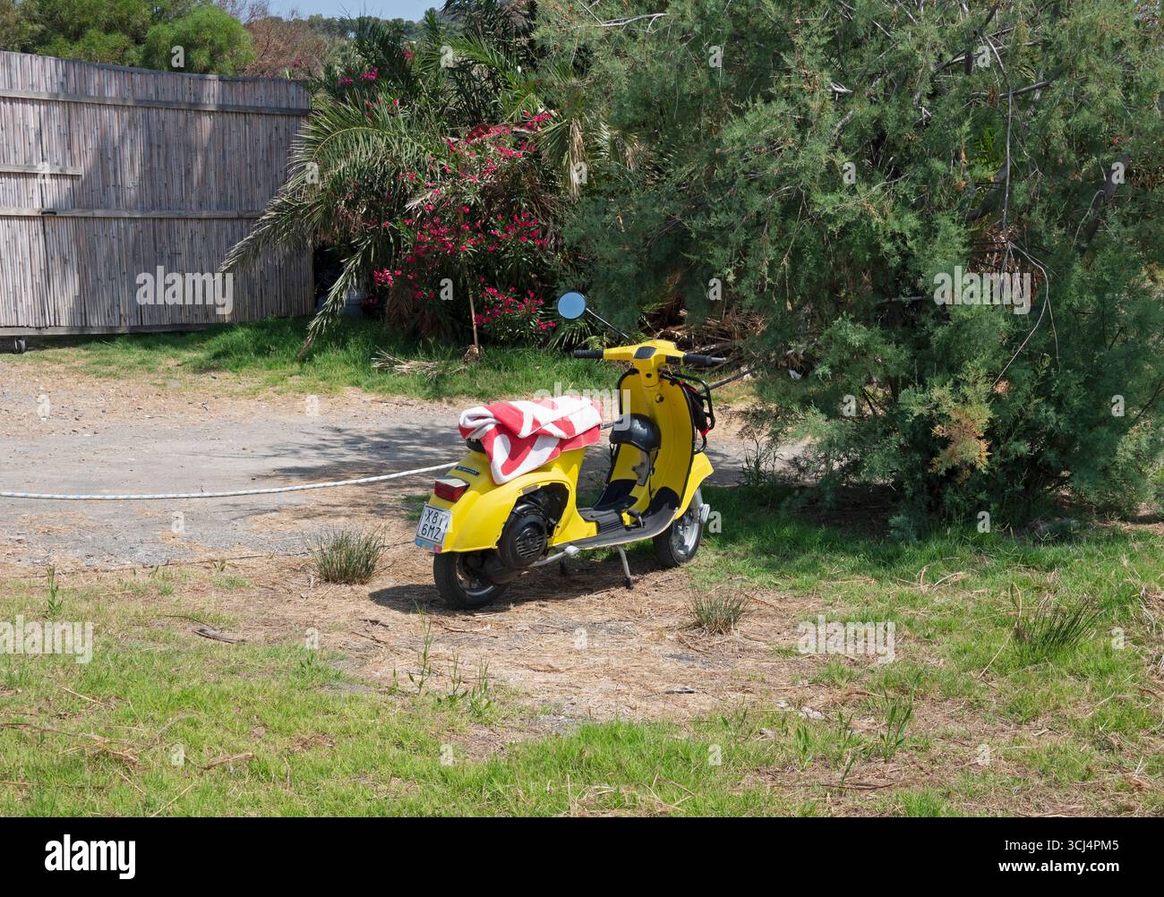 Vespa gialla con telo mare in sella parcheggiata in un cortile, Italia Foto Stock