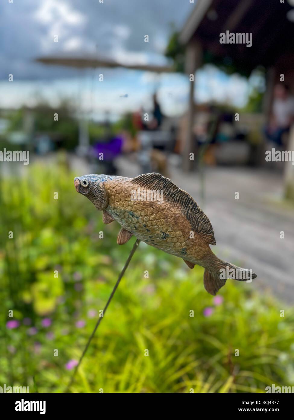 Scultura decorativa di pesci in un giardino con sfondo sfocato, scena estiva in Francia Foto Stock