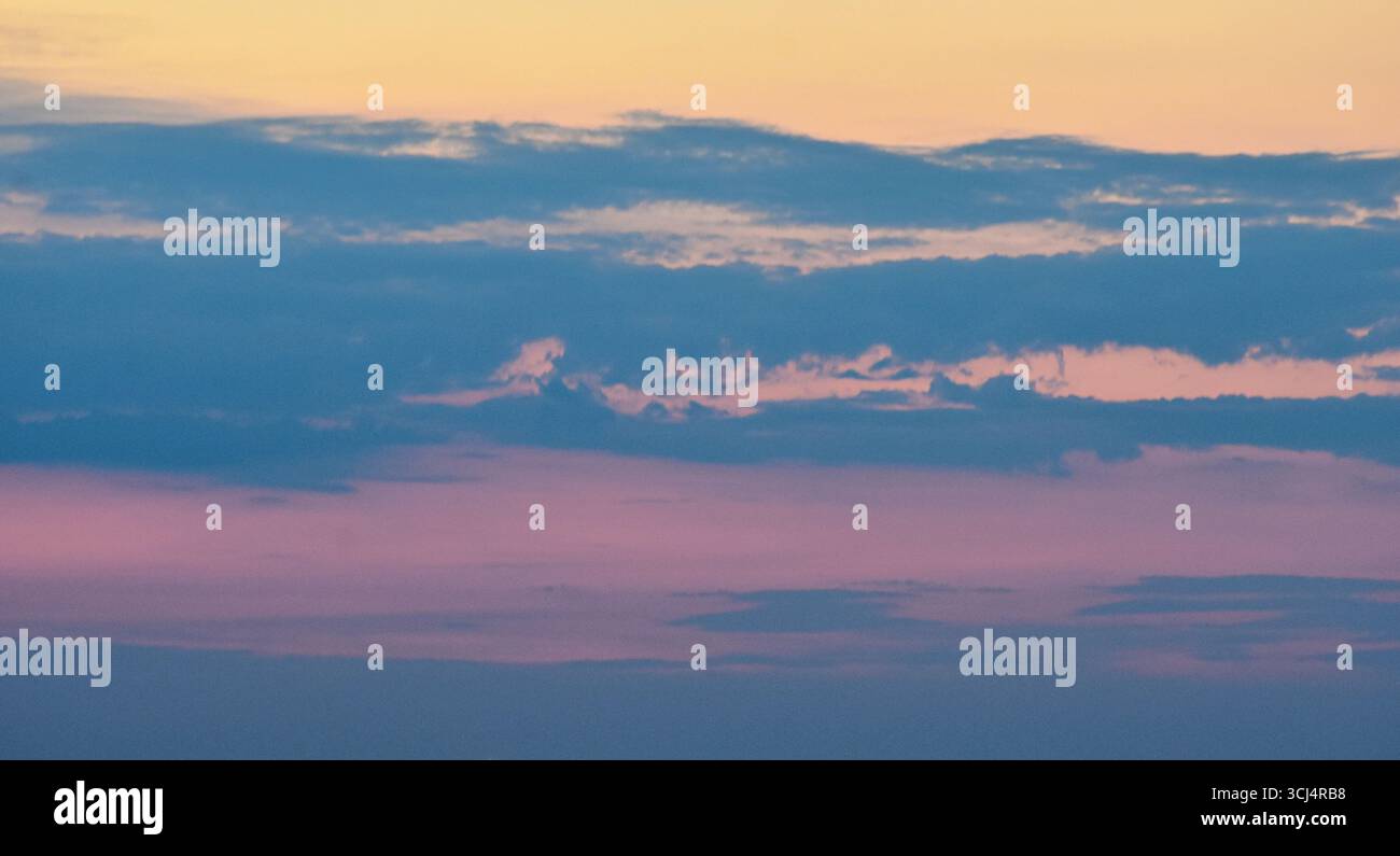 Un cielo affascinante al tramonto, con nuvole scintillanti e colori surreali, crea un'atmosfera serena e magica. Foto Stock