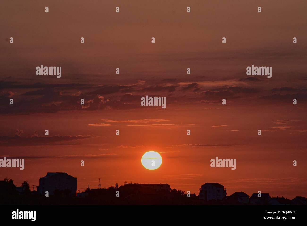 Il cielo serale colorato sopra edifici sagomati durante il tramonto, mostra l'armonia tra la vita cittadina e la bellezza pacifica della natura. Foto Stock