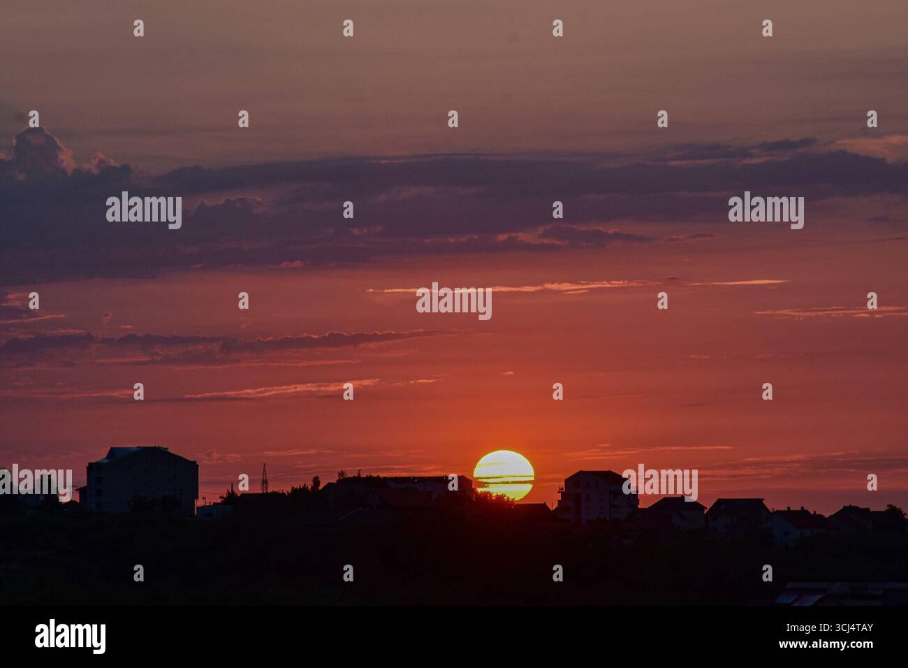 Tramonta sullo skyline della città con magici colori del cielo, luce soffusa e silhouette urbane nella calda luce della sera. Foto Stock