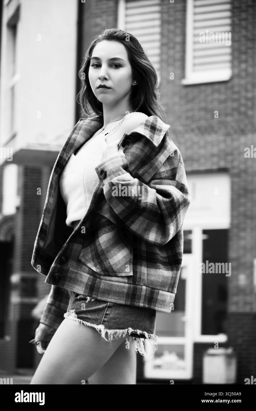 Giovane donna attraente che posa per la strada autunnale, monocromatica Foto Stock