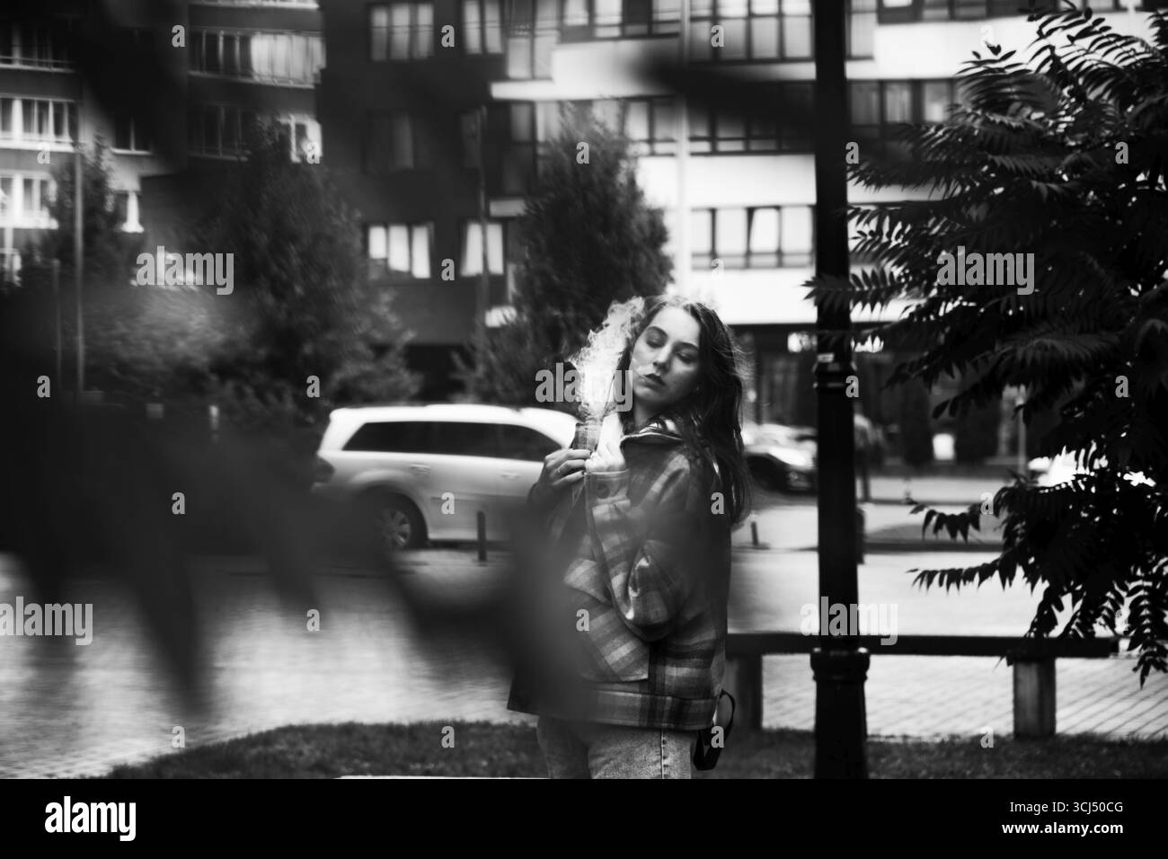 Giovane donna attraente che posa per la strada autunnale, monocromatica Foto Stock