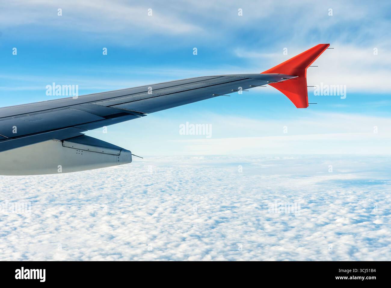 Vista dalla finestra di un aereo che presenta l'ala sullo sfondo di cielo blu e soffici nuvole bianche Foto Stock