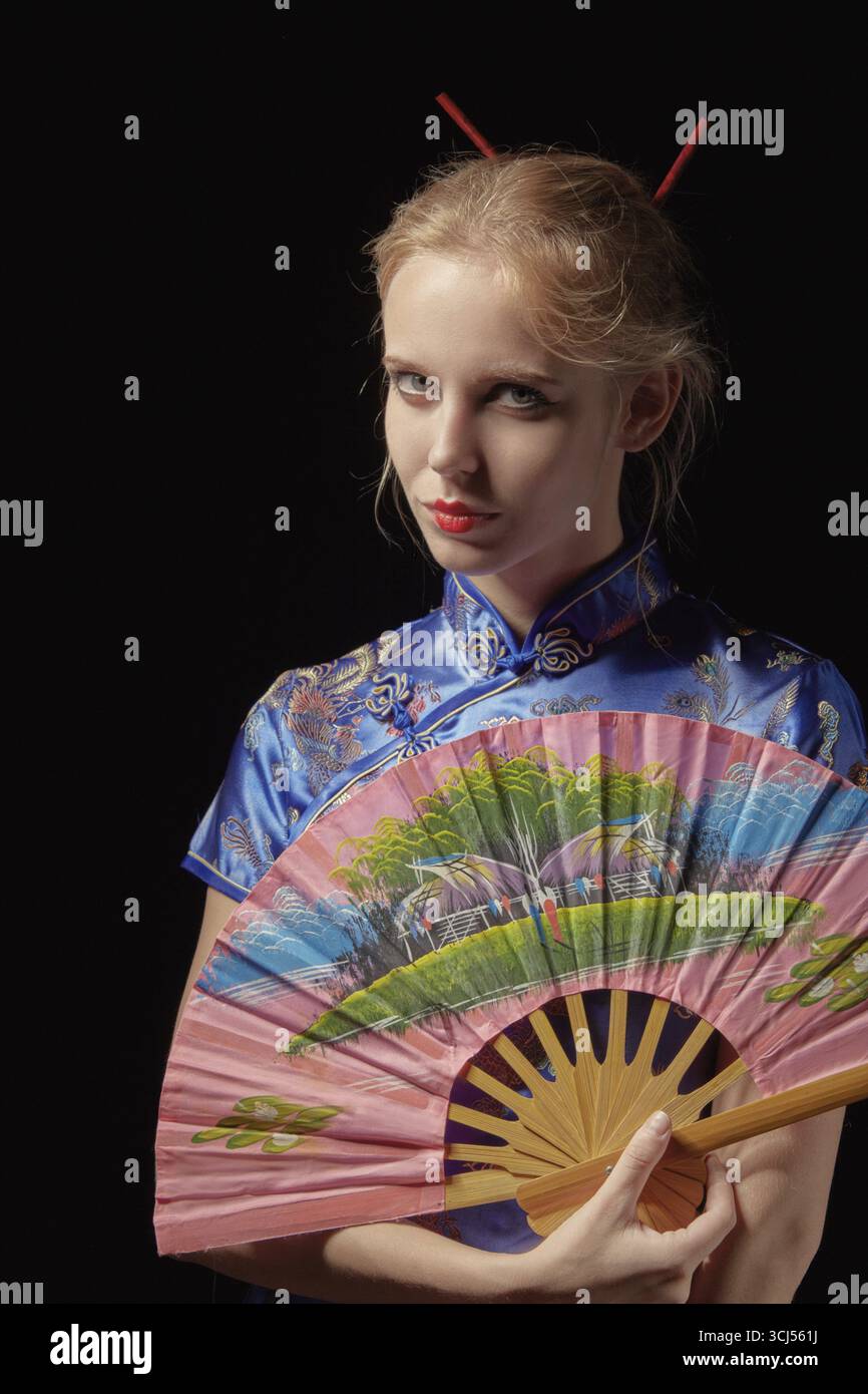 Ragazza in abito giapponese con ventilatore su sfondo nero Foto Stock
