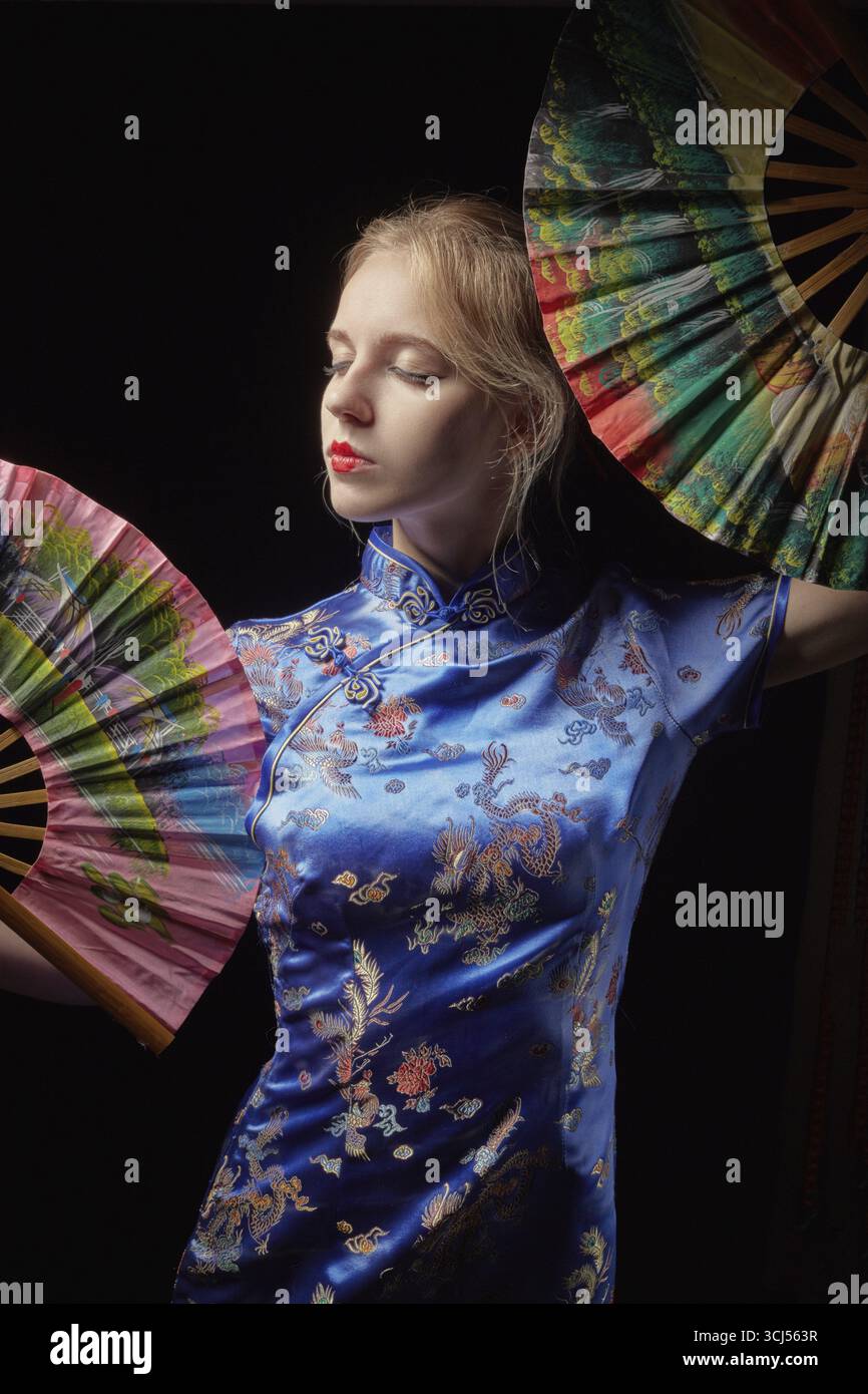 Ragazza in abito giapponese con ventilatore su sfondo nero Foto Stock
