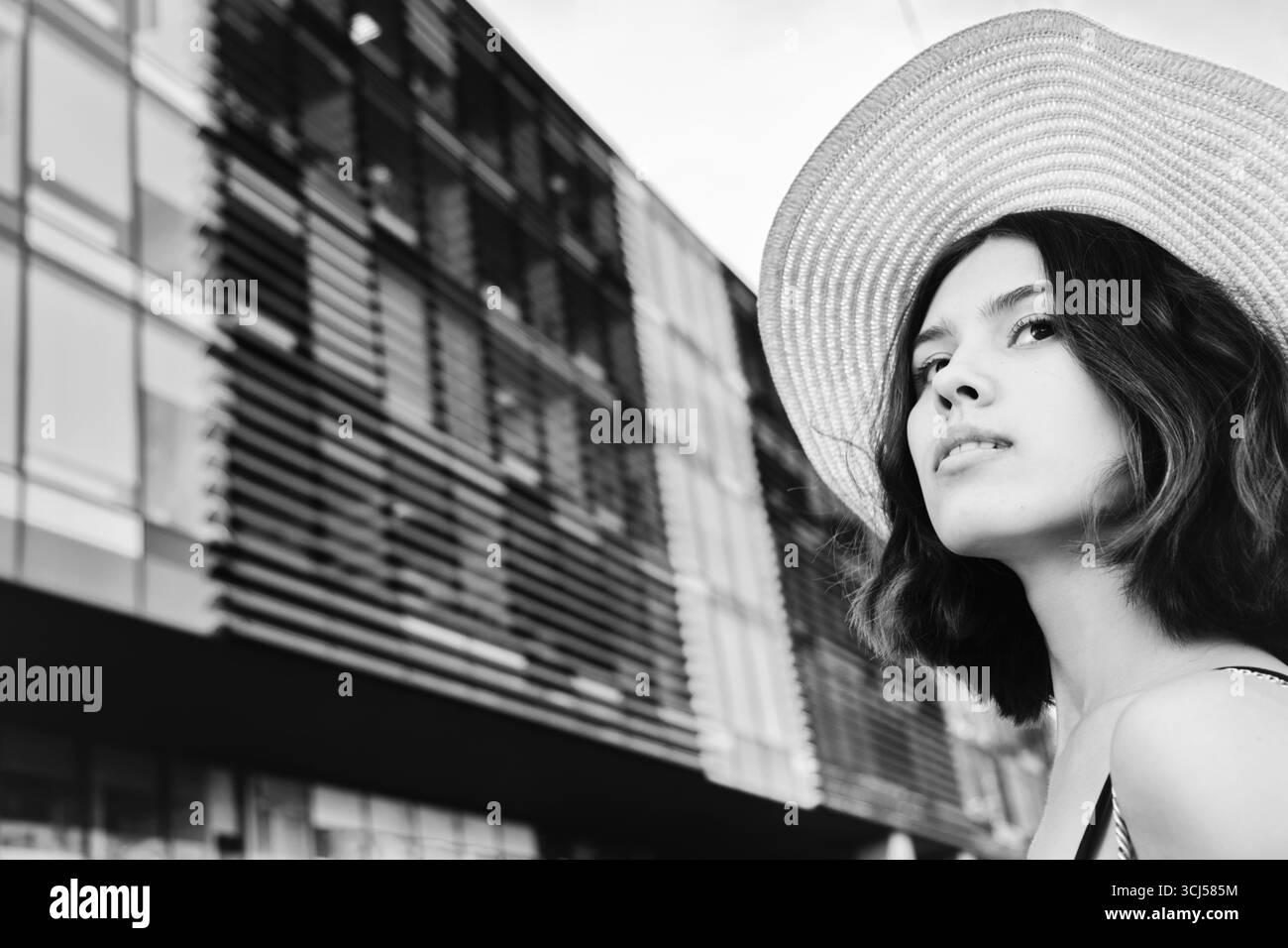 Giovane donna attraente in cappello al ritratto di primo piano della città, monocromatico Foto Stock