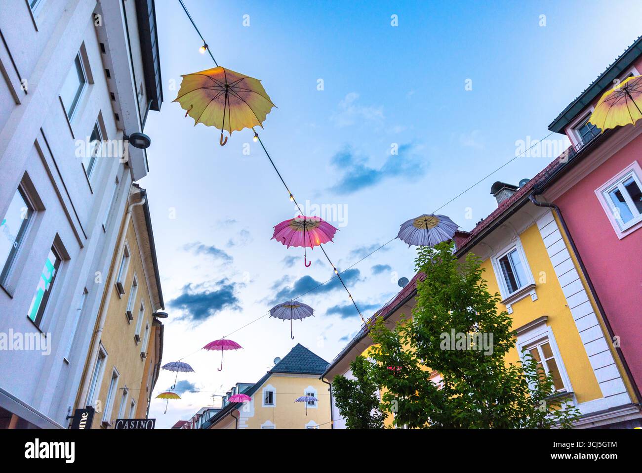 Villach, Austria - 22 giugno 2024: Ombrelli decorativi appesi sopra la strada della città vecchia che creano una colorata atmosfera estiva a Villach Foto Stock