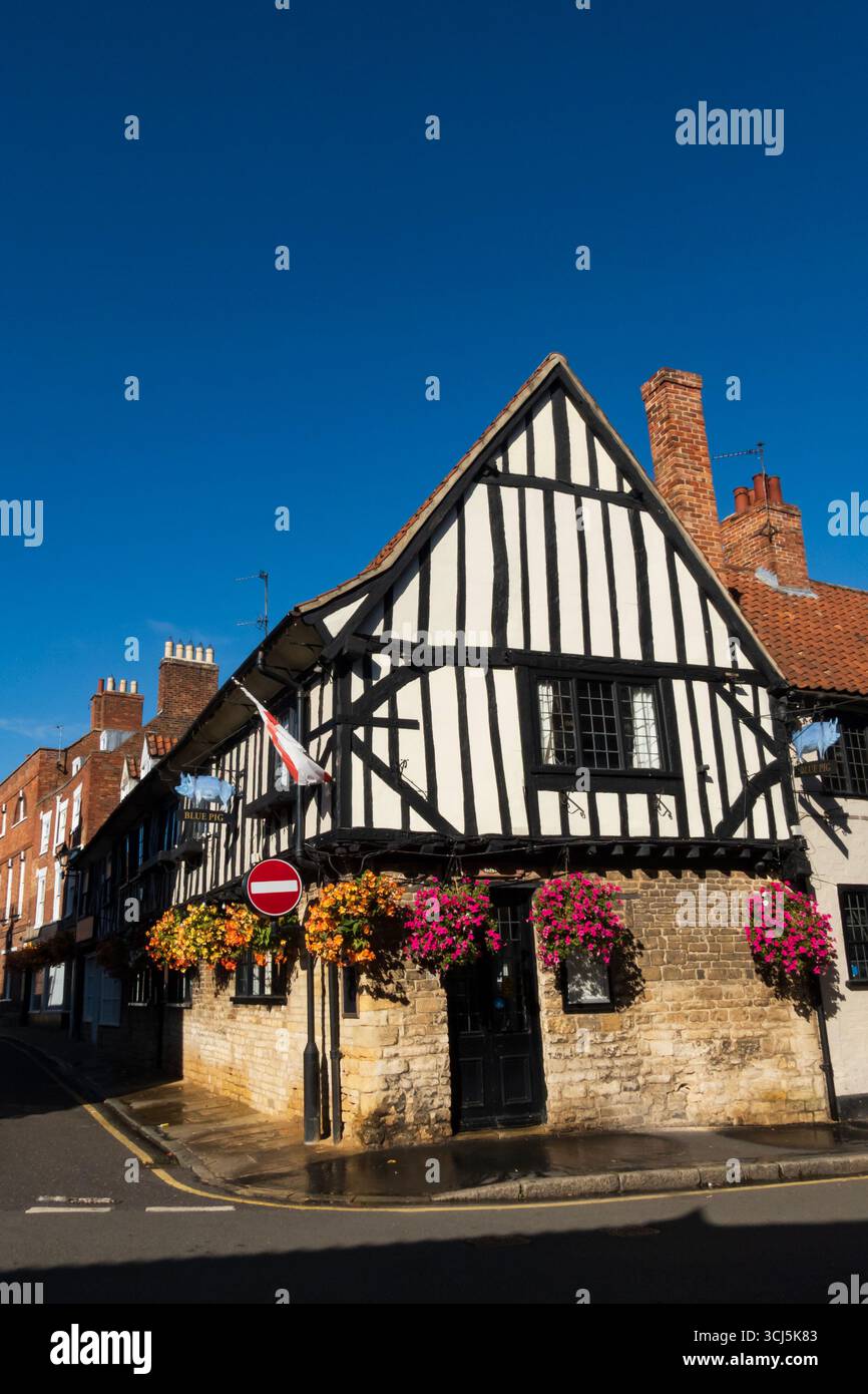 La casa pubblica Blue Pig a Vine Street, Grantham, Lincolnshire, Inghilterra. Decorata con cesti sospesi in fiore e un cielo estivo blu luminoso. Foto Stock