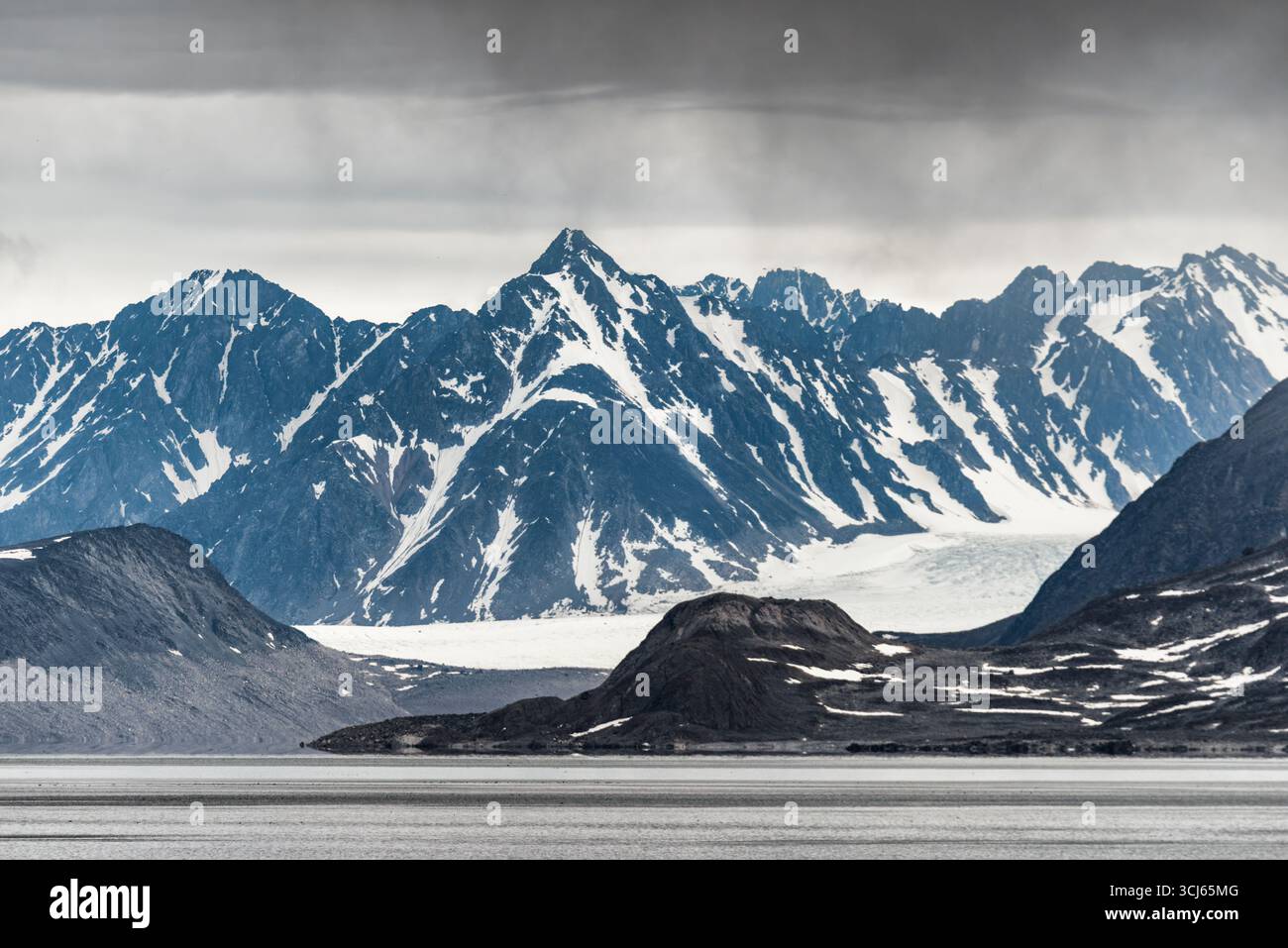 Montagne innevate e ghiacciaio a Fairhaven Svalbard // SVALBARD, Norvegia: Montagne innevate e un ghiacciaio dominano il suggestivo paesaggio delle Svalbard, un arcipelago artico situato nell'Oceano Artico. Questo remoto territorio norvegese è noto per il suo terreno accidentato, i ghiacciai e la fauna selvatica unica. La dura bellezza delle cime innevate e la vasta distesa di ghiaccio evidenziano l'ambiente estremo di questa regione ad alta latitudine. Le Svalbard fanno parte della regione amministrativa norvegese delle Svalbard e Jan Mayen, contribuendo al suo status di destinazione significativa per l'esplorazione polare Foto Stock