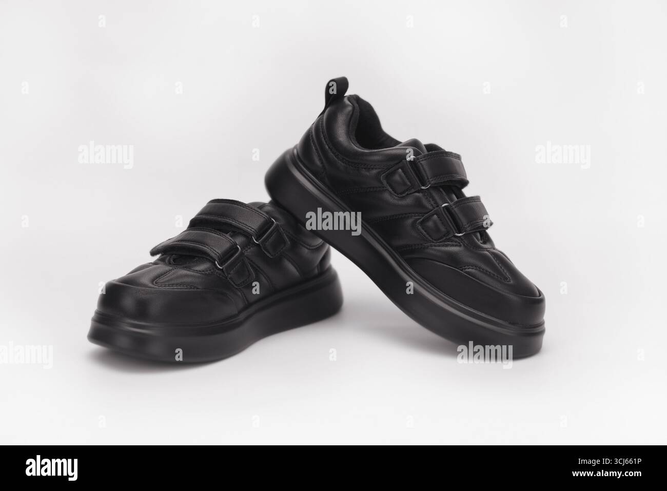 Eleganti sneaker nere con cinturini in velcro, progettate per il massimo comfort e facilità d'uso, esposte su uno sfondo bianco e pulito, che rappresenta il moderno Foto Stock