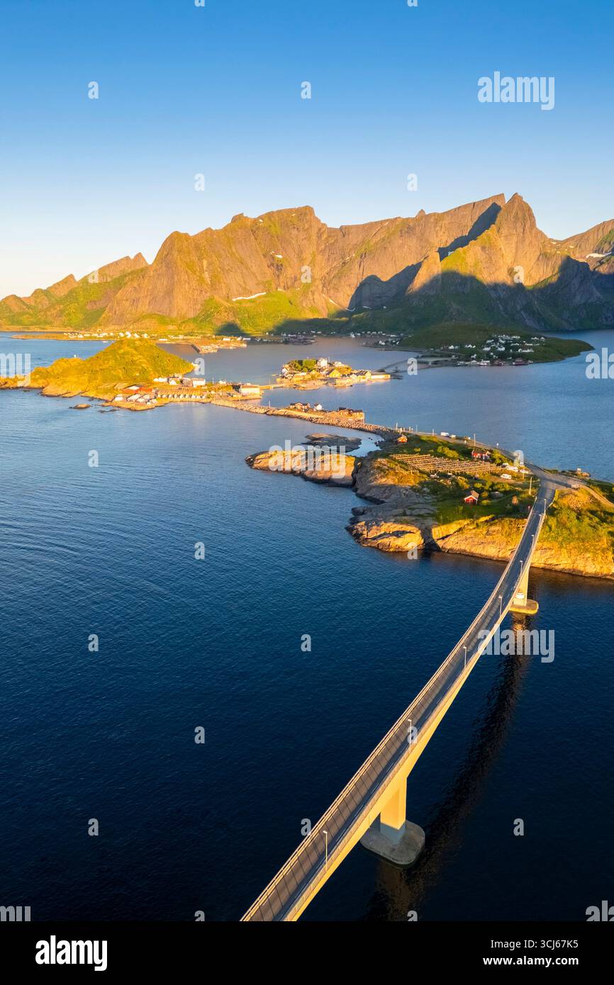Vista aerea dell'isola di Sakrisøya e della baia di Reine verso Reinebringen in estate all'alba durante il sole di mezzanotte. Isole Lofoten, Norvegia. Foto Stock