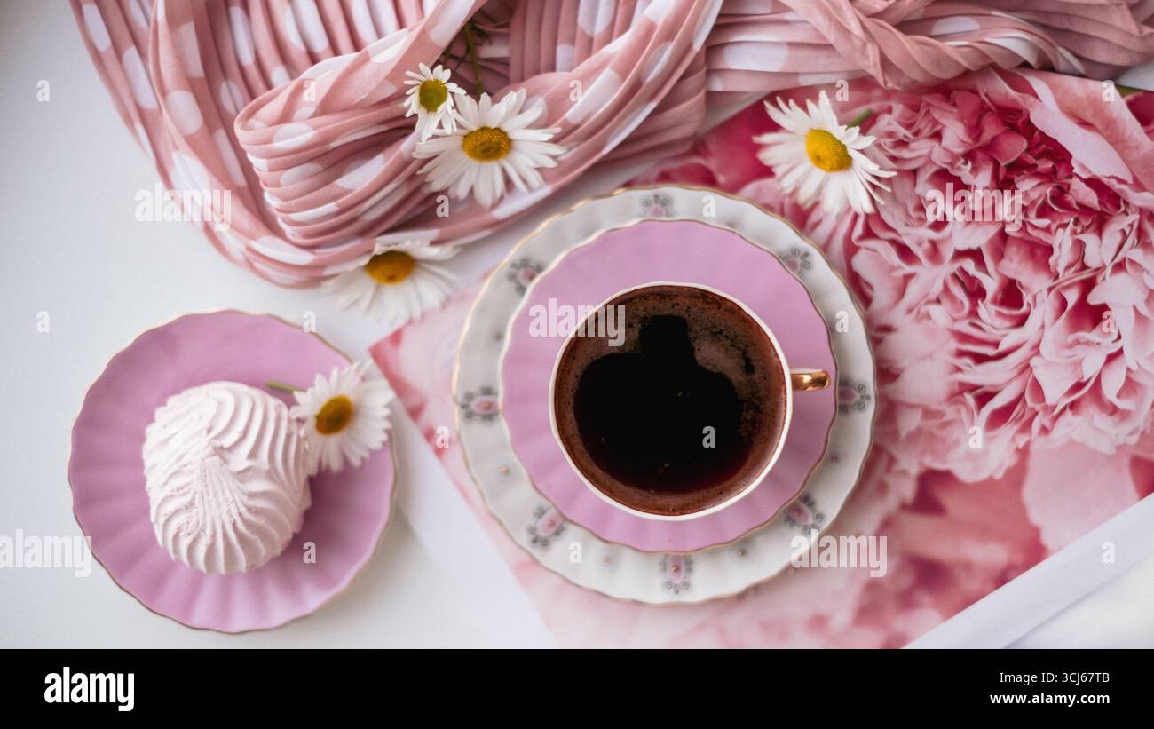 L'elegante decorazione rosa mette in mostra un delizioso dessert e caffè, circondato da accenti floreali e tessuti morbidi, invitando un ambiente accogliente per il dolce Foto Stock