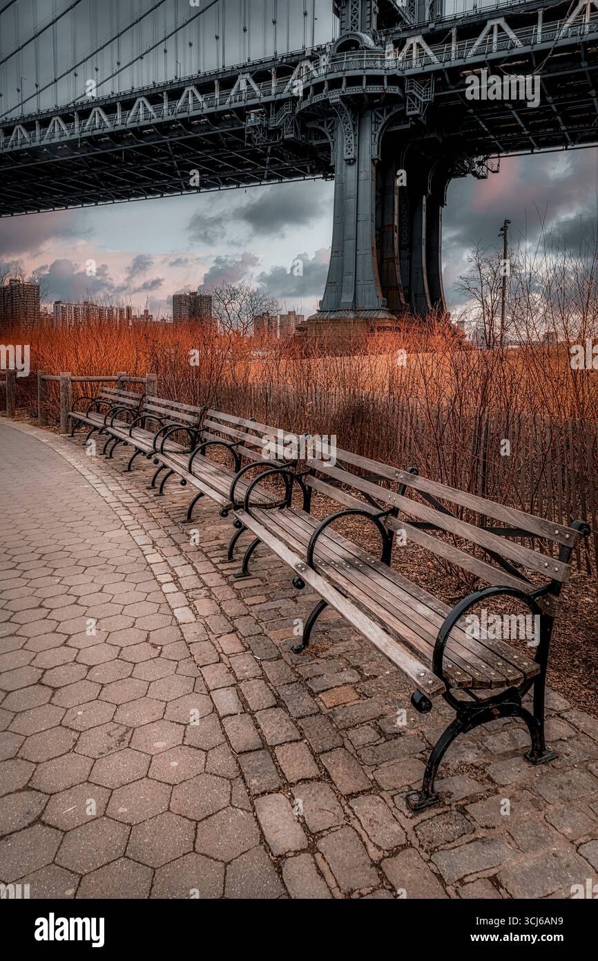 D U M B o Brooklyn NY - sotto il ponte al Brooklyn Bridge Park con vista sul Manhattan Bridge Bridge, con panchine in legno. Foto Stock