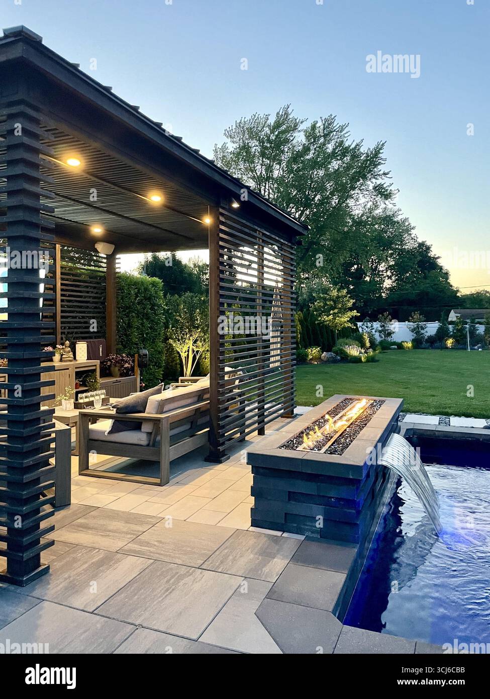 Spazio abitativo moderno e di lusso per tutta la stagione. Caminetto, piscina a forma di J, solarium, cascata, mobili. Pergola, set da pranzo al padiglione, sala Foto Stock