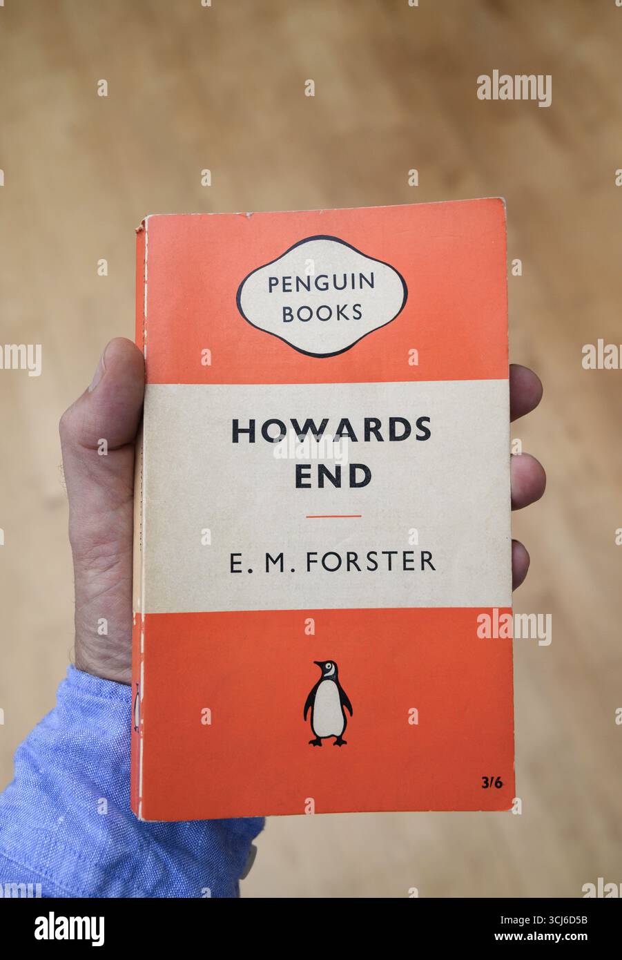 Mano che tiene in mano un vecchio libro cartaceo dei Pinguini di Howards End di EM Forster Foto Stock