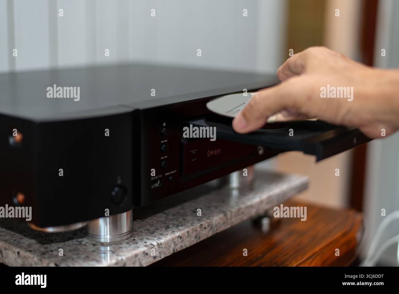 Primo piano di una mano che inserisce un compact disc in un lettore CD Hi-Fi, evocando un momento nostalgico di musica analogica. Foto Stock