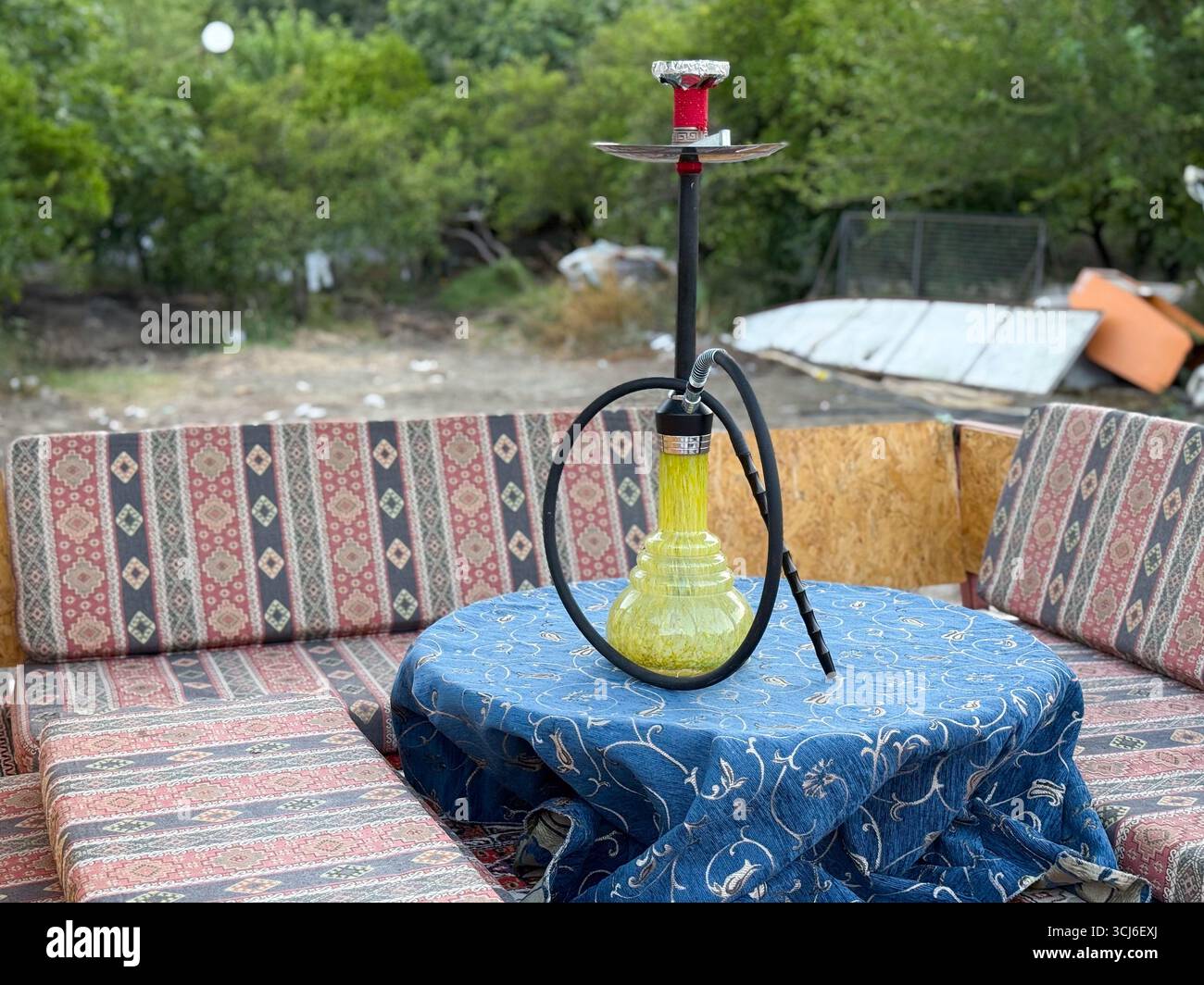 Narghilè su un tavolo decorato con posti a sedere a motivi geometrici. Cultura, tradizione e stile di vita per il relax sociale, il fumo rituale e la riunione di svago Foto Stock