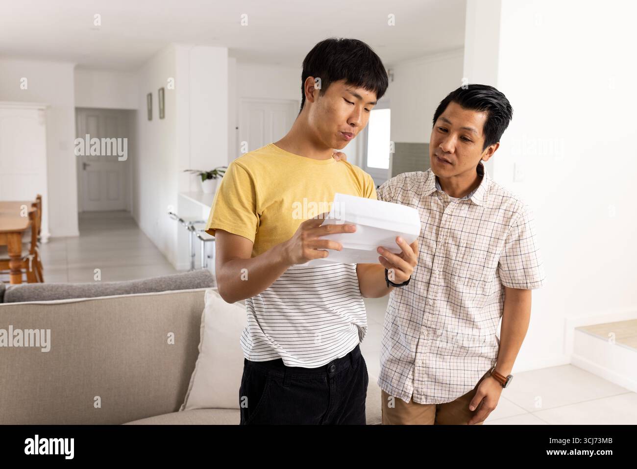 Padre e figlio leggono una lettera a casa, discutendo di notizie importanti Foto Stock